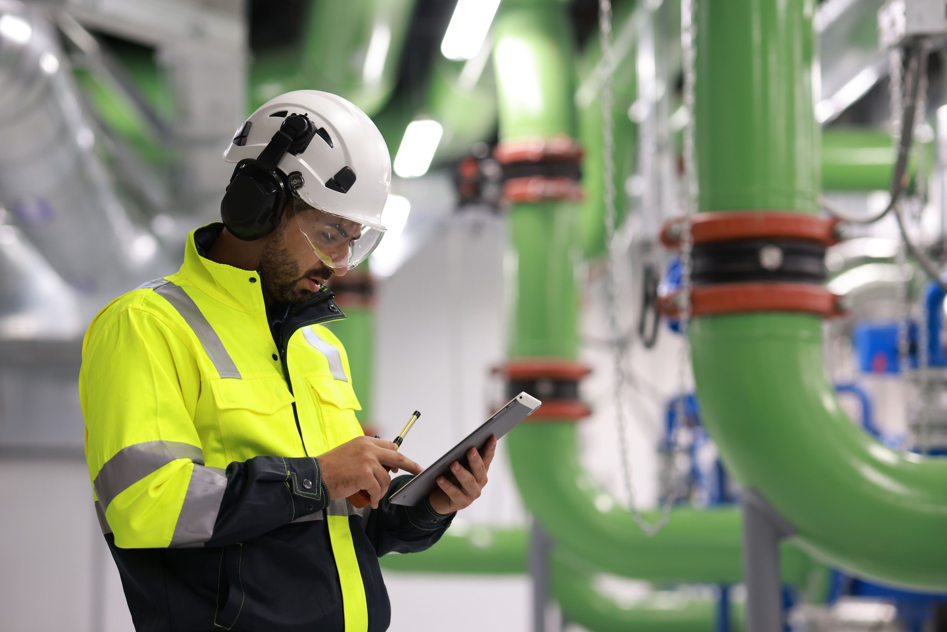 Male Industrial Engineers working with Project Blueprints drawing at front heavy industrial machinery, HVAC system engineer